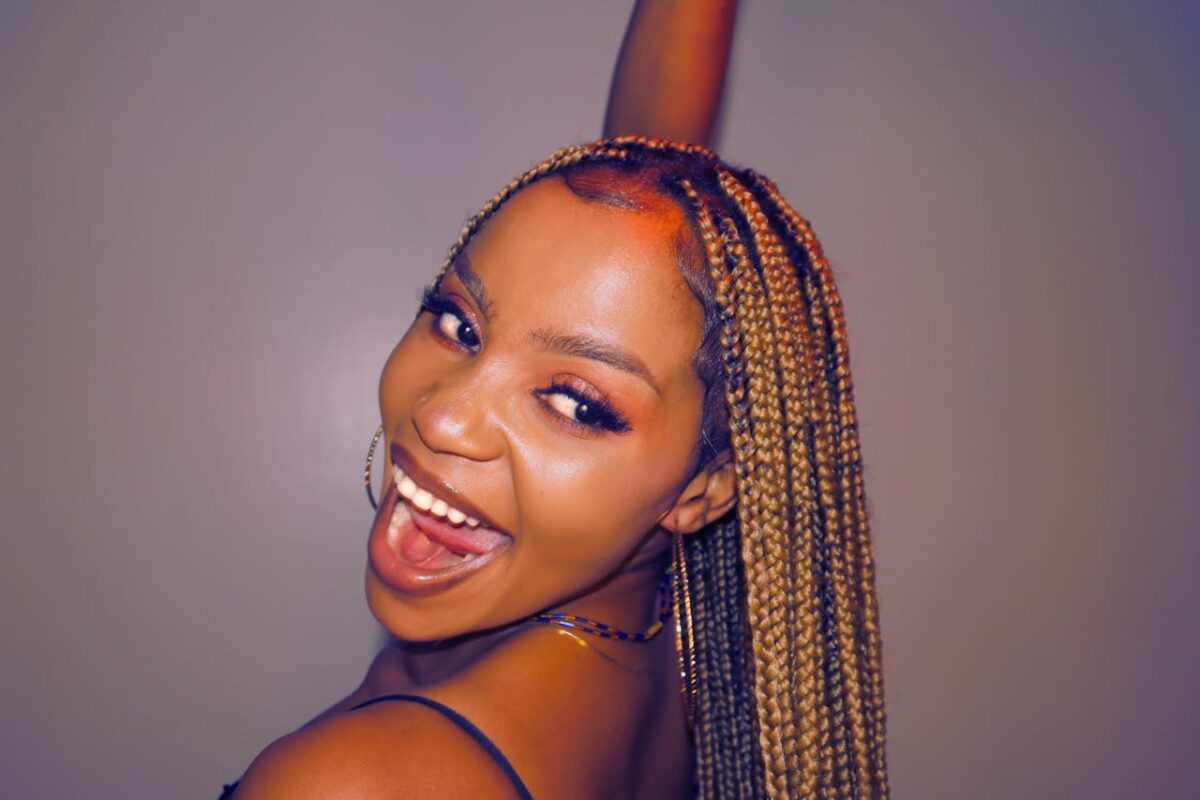 Vibrant portrait of an African woman with braided hair, exuding joy and style.