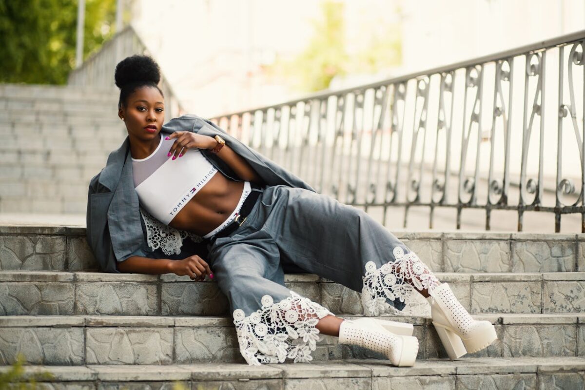 Elegant woman in trendy attire poses confidently on outdoor stairs, displaying modern fashion.