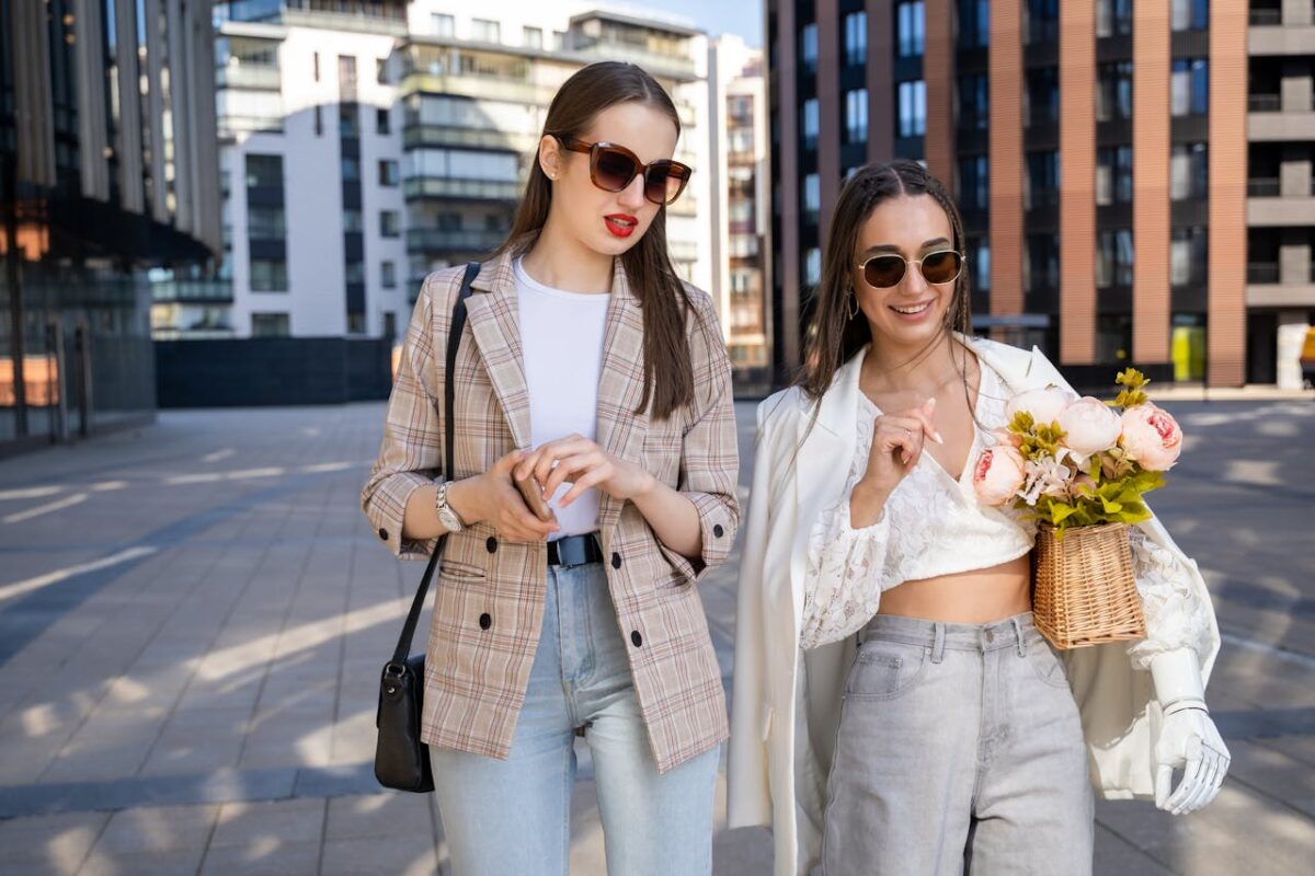 Two fashionable women enjoying a sunny day in the city, showcasing modern style and friendship.